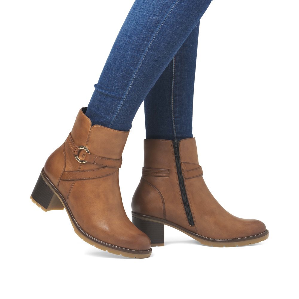 Wood brown remonte women´s ankle boots D2A73-24 with a round decorative buckle. Shoe on foot.