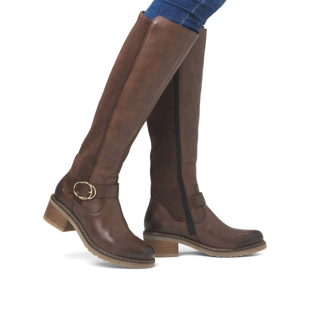 Chocolate brown remonte women´s high boots D1A73-25 with a round decorative buckle. Shoe on foot.