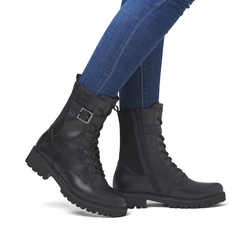 Black remonte women´s biker boots D8664-00 with decorative buckle as well as zipper. Shoe on foot.