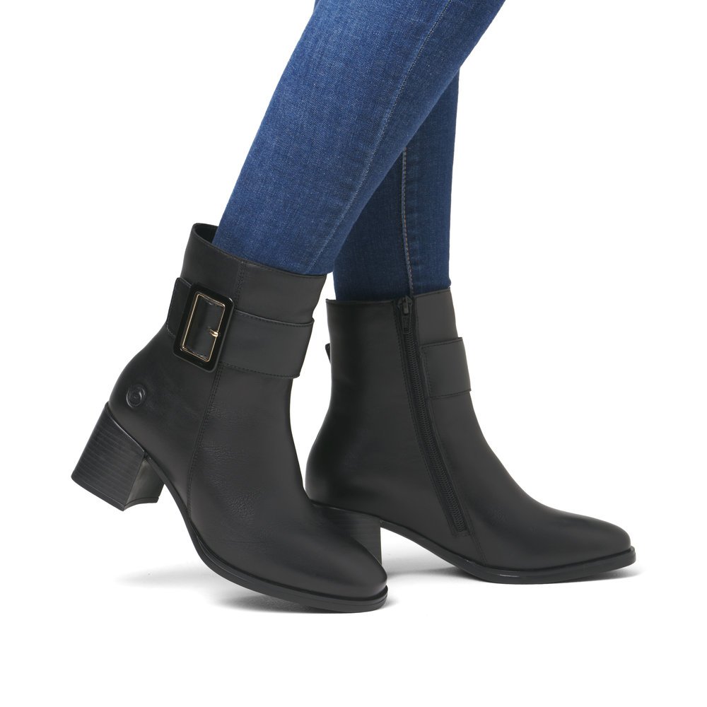 Black remonte women´s ankle boots D0V80-00 with decorative buckle as well as zipper. Shoe on foot.