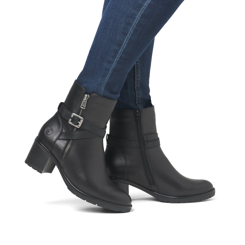 Black remonte women´s ankle boots D2A72-00 with decorative buckle as well as zipper. Shoe on foot.