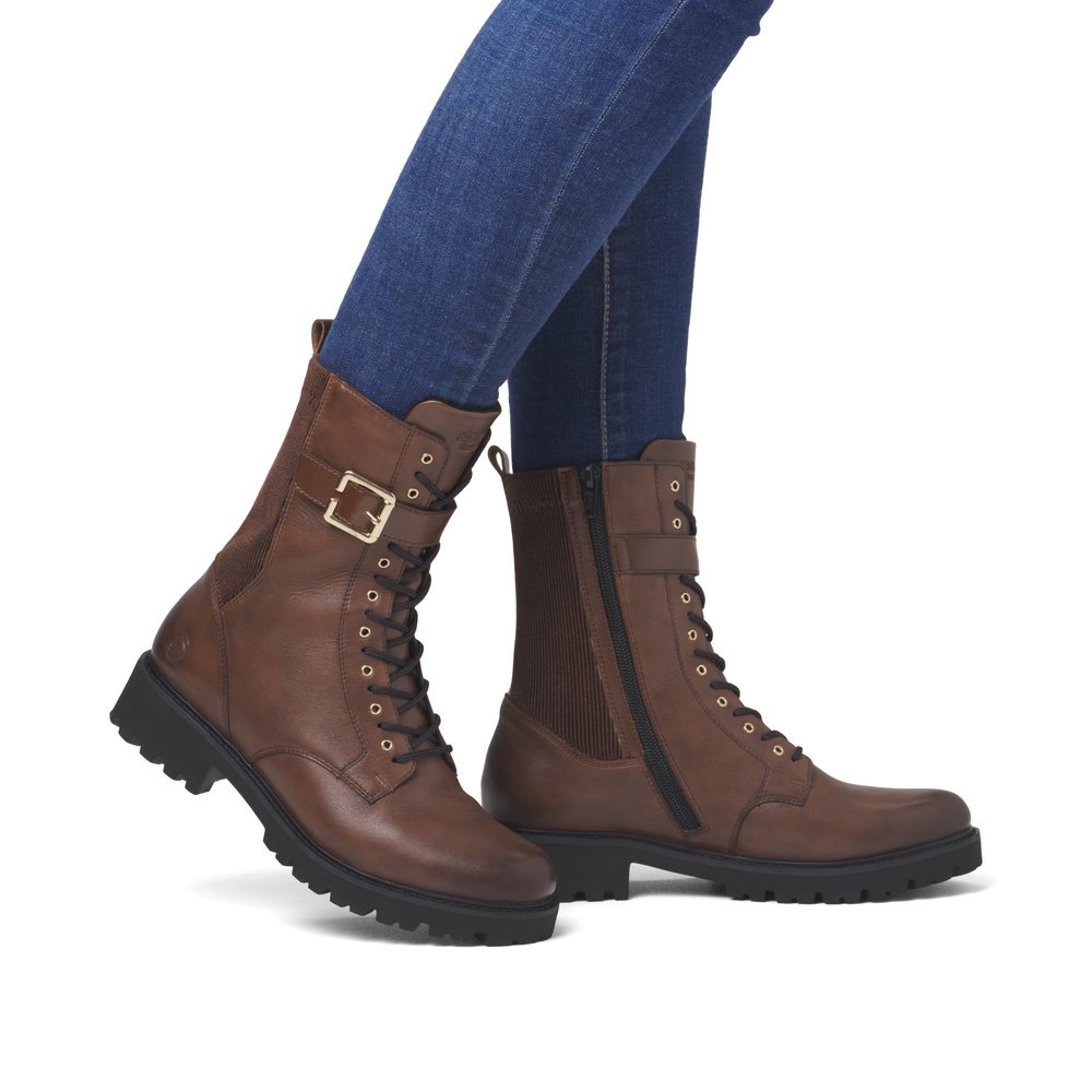 Brown remonte women´s biker boots D8664-25 with decorative buckle as well as zipper. Shoe on foot.