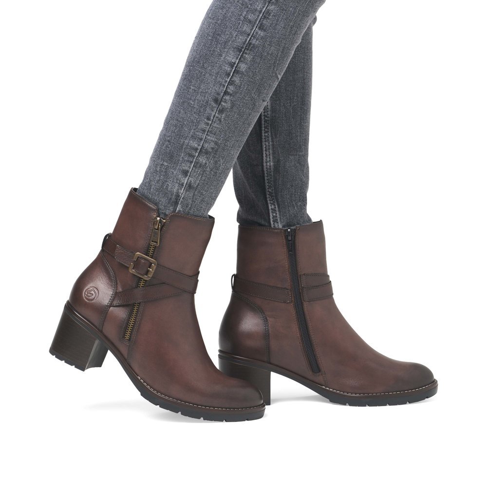 Brown remonte women´s ankle boots D2A72-25 with decorative buckle as well as zipper. Shoe on foot.