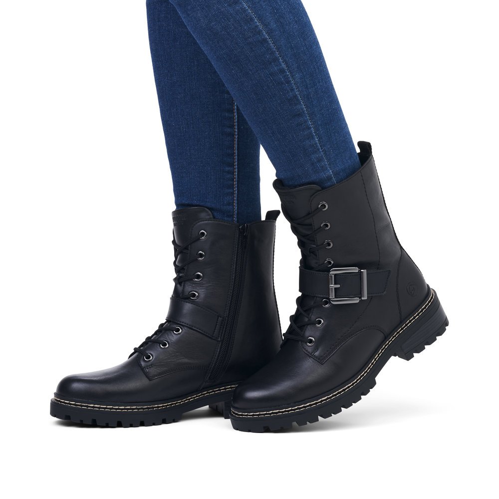 Night black remonte women´s biker boots D0B78-01 with strap with decorative buckle. Shoe on foot.