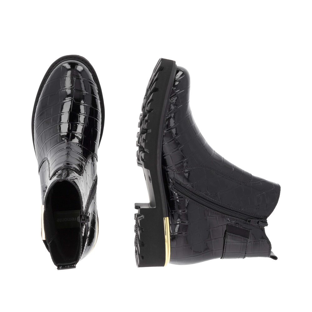 Lacquer black remonte women´s Chelsea boots D8684-03 with golden decorative element. Shoe from the top, lying.