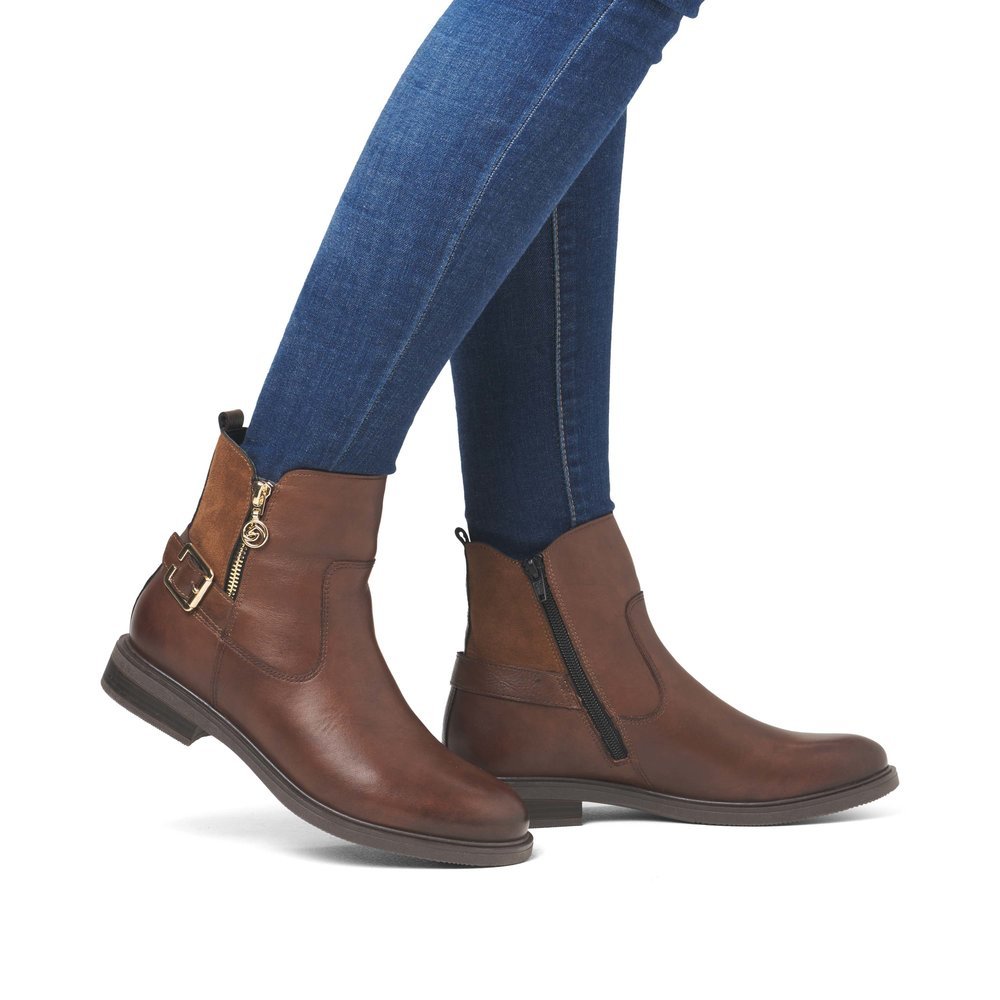 Brown remonte women´s ankle boots D1U71-22 with a golden decorative buckle. Shoe on foot.