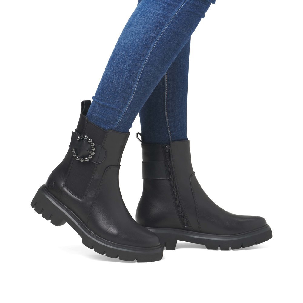 Jet black remonte women´s Chelsea boots D1W74-00 with a round decorative buckle. Shoe on foot.