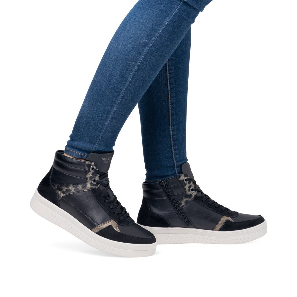 Asphalt black remonte women´s sneakers D0J71-03 with animal print as well as zipper. Shoe on foot.