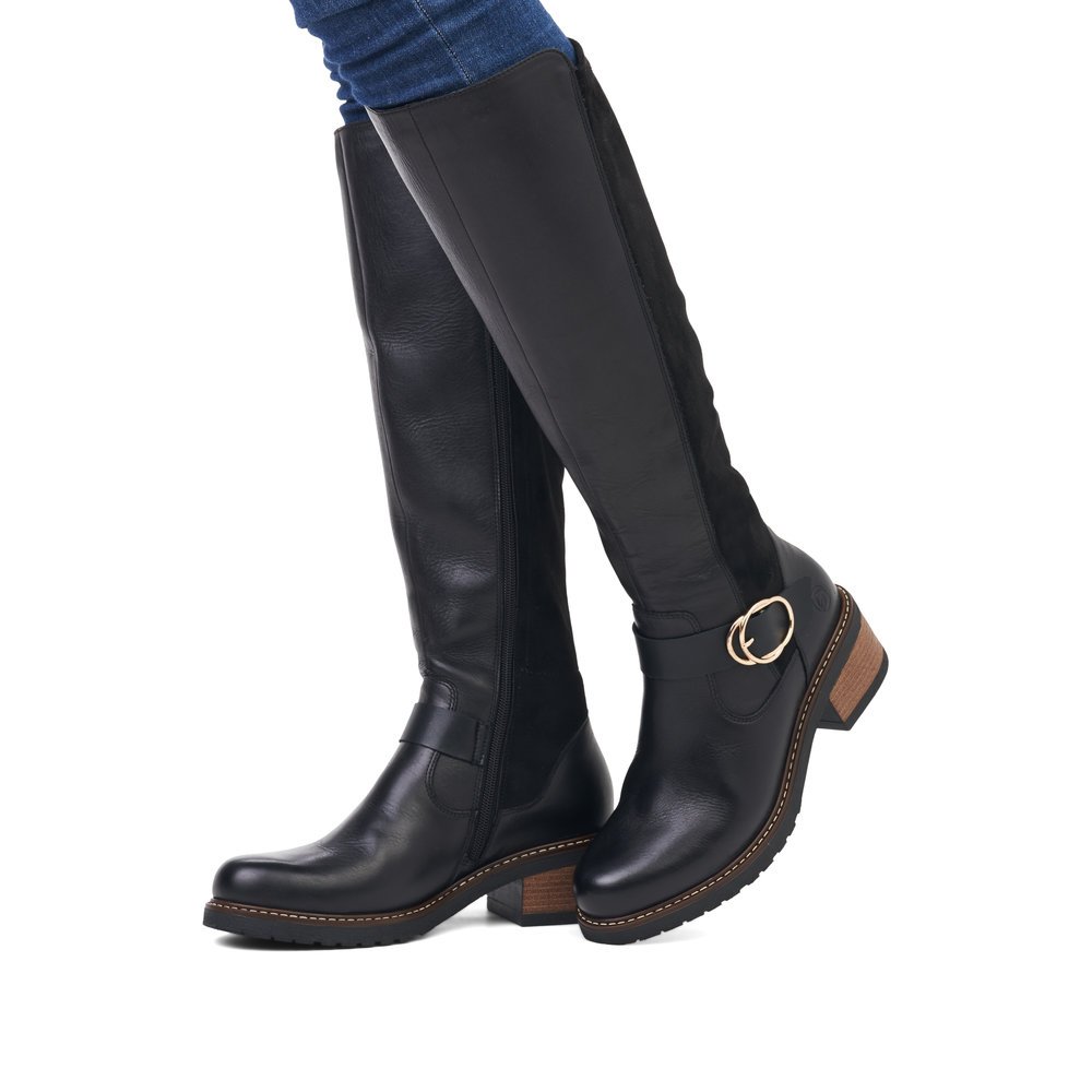 Jet black remonte women´s high boots D1A73-01 with a round decorative buckle. Shoe on foot.