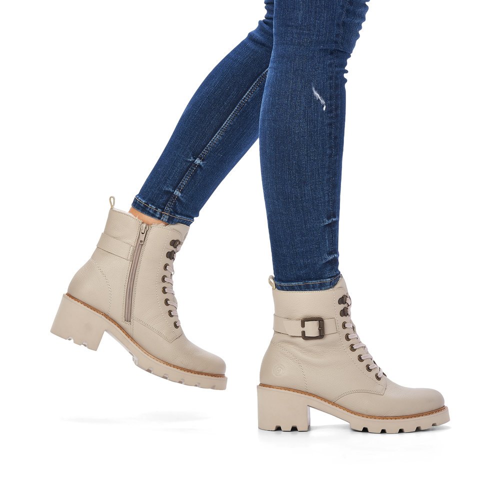 Beige remonte women´s biker boots D0A74-60 with decorative buckle as well as zipper. Shoe on foot.