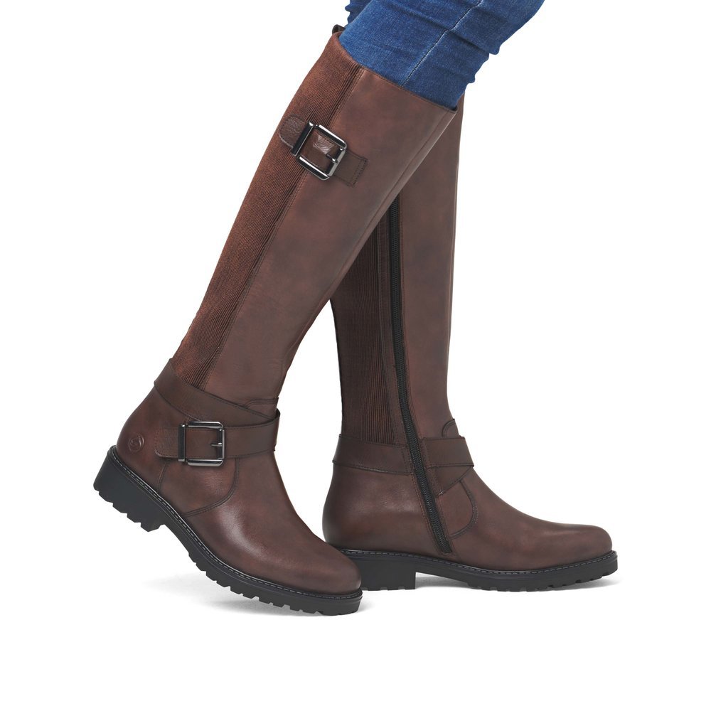 Brown remonte women´s high boots R6593-25 with decorative buckles as well as zipper. Shoe on foot.