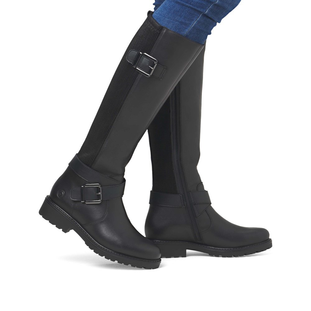 Black remonte women´s high boots R6593-00 with decorative buckles as well as zipper. Shoe on foot.