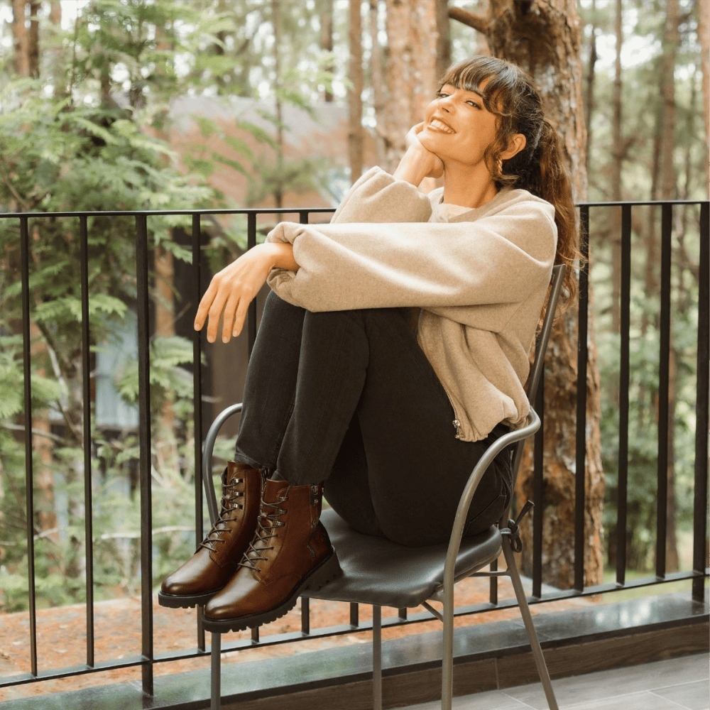Frau sitzt draußen mit Herbst Outfit und braunen remonte Schnürstiefel