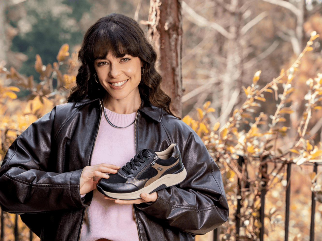 Frau hält schwarz braunen Sneaker in den Händen von remonte.