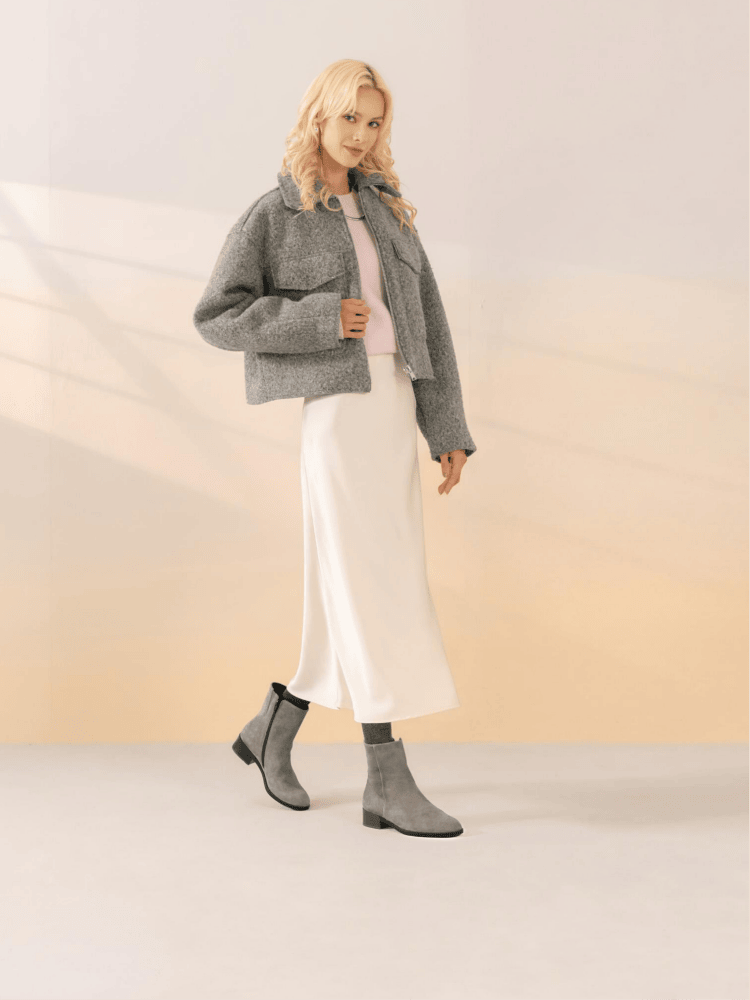Frau in schicken Outfit mit Rock und graue Rauleder Stiefeletten von remonte