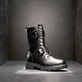 Tiefschwarze remonte Damen Biker Boots D1W70-00 mit runden Zierschnallen. Schuh auf dunklem Hintergrund.