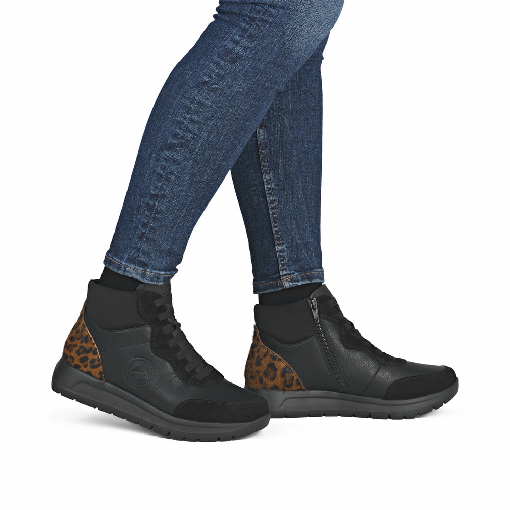 Schwarze remonte Damen Kurzstiefel D2V70-03 mit Leo-Print sowie Reißverschluss. Schuh am Fuß.