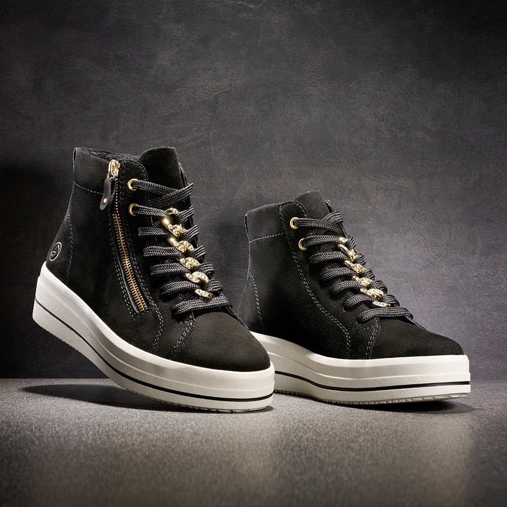 Schwarze remonte Damen Sneaker D1C70-02 mit Kettenelement sowie Reißverschluss. Schuhe auf schwarzem Hintergrund.