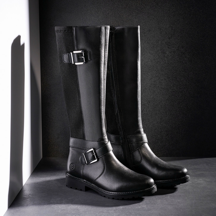 Nachtschwarze remonte Hochschaftstiefel R6593-00 mit Zierschnallen. Schuhe auf dunklem Hintergrund.