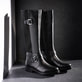 Nachtschwarze remonte Hochschaftstiefel R6593-00 mit Zierschnallen. Schuhe auf dunklem Hintergrund.
